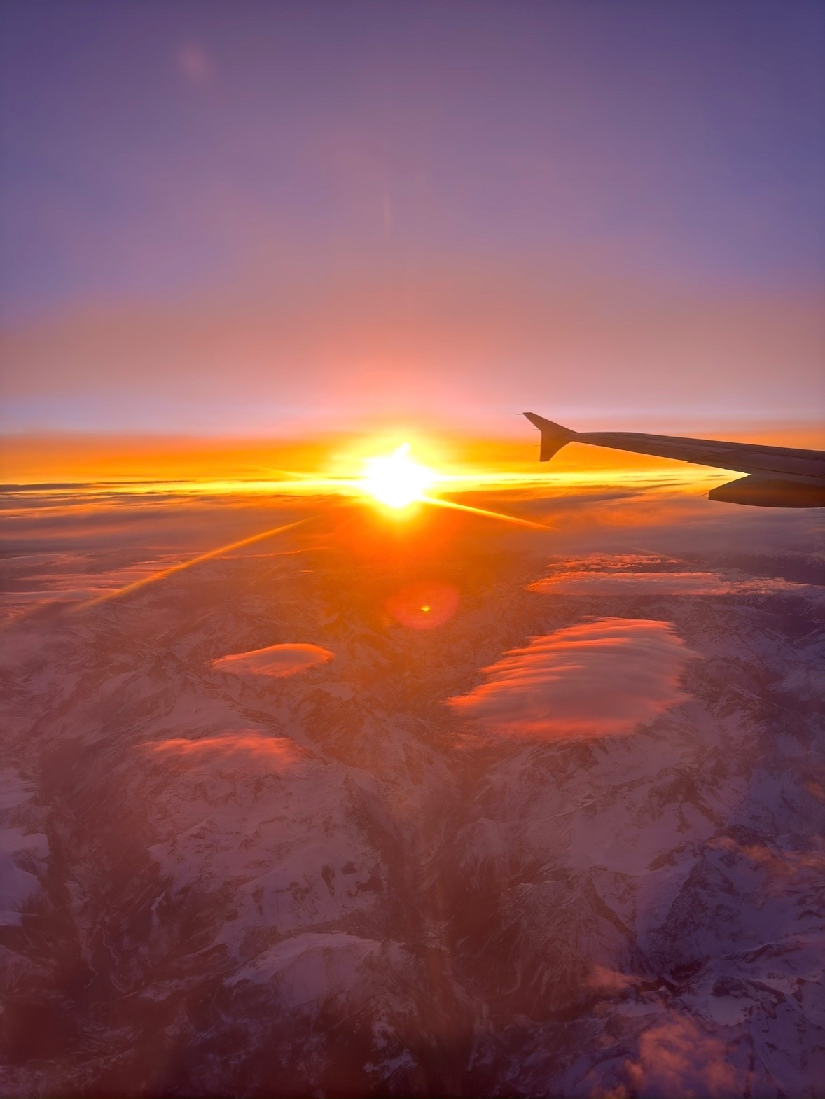 Sonnenuntergang über den Alpen aus einem Flugzeugfenster